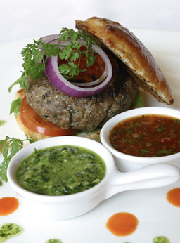 Beefburger on a bun with assorted dips.