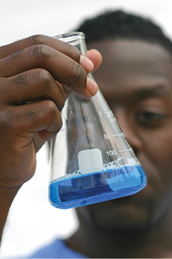 Photo of a student holding a beaker with a blue solution